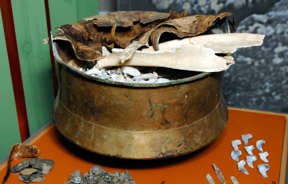 I bronskitteln finns brända ben från två individer som kremerats och begravts tillsammans under folkvandringstid. Kitteln är utställd i Forntider.