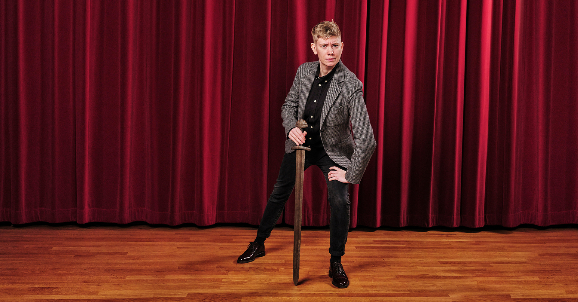 Moa Svan poserar med en svärd framför ett rött teaterdraperi