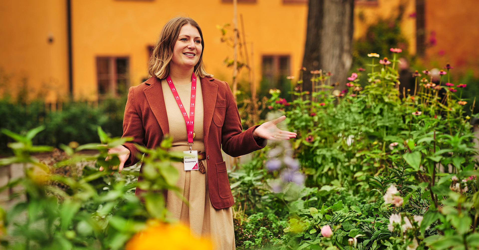 Museipedagog Elisabet Ryd står utomhus bland blommor.