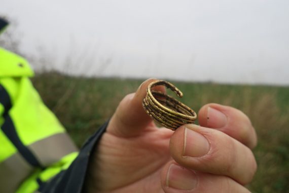 En hand hållandes ett nyligen uppgrävt spiralformat föremål av guld