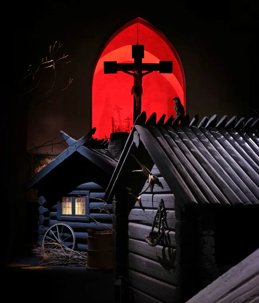 Stugor och ett kors upplyst i rött