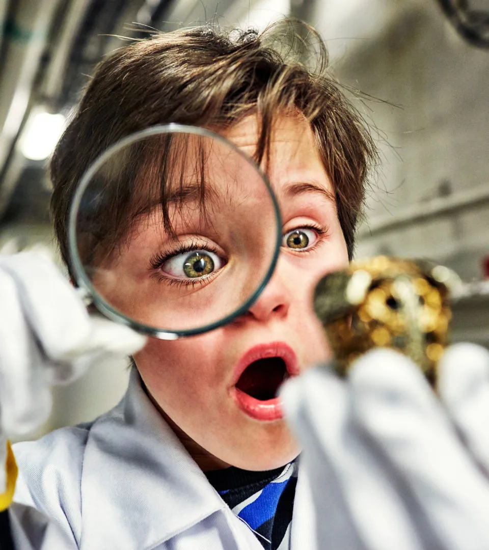 Barn tittar på ett föremål genom ett förstoringsglas.