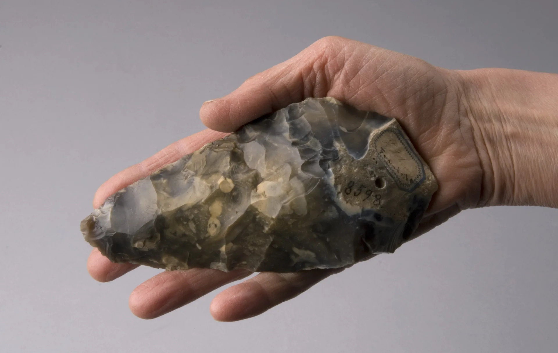 A human hand holding a piece of flint