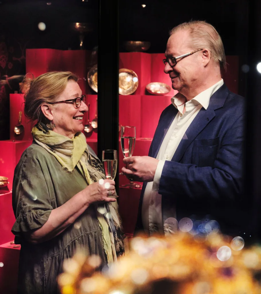 Två personer står i Guldrummet. De skålar i varsitt champagneglas.