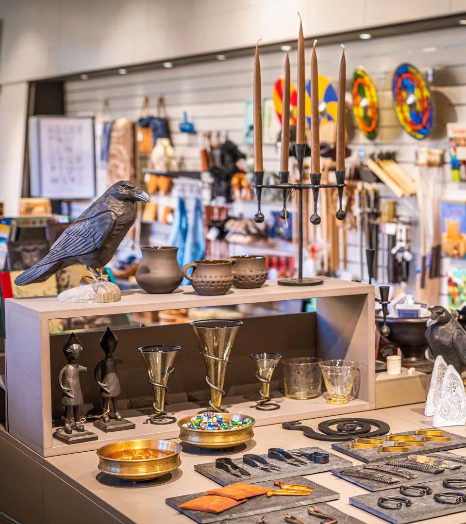 Vy över en butik med en korpdekoration och en ljusstake. På ett bord ligger varor prydligt uppradade.