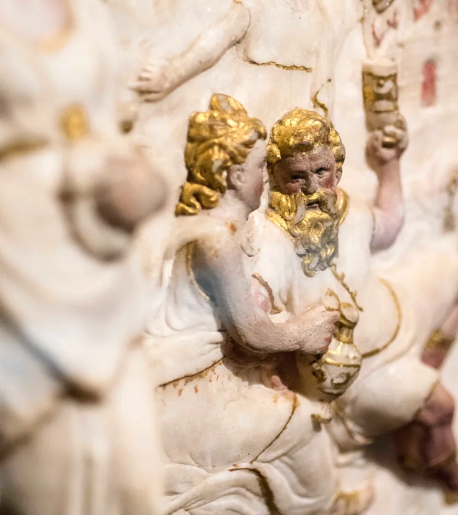 Detaljbild på en skulptur. Två festande personer.