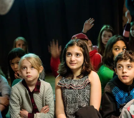 arn sitter på golvet och lyssnar på en pedagog. Några räcker upp handen.