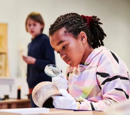 Barn undersöker ett föremål med ett förstoringsglas.