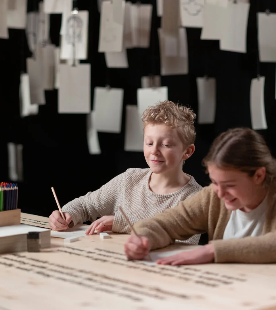 Två barn sitter och skriver i utställningen Tillsammans genom tiden.