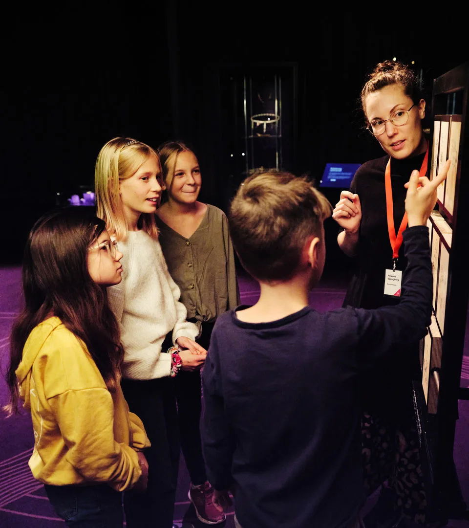 En pedagog håller i en visning för en grupp skolelever i utställningen Vikingarnas värld.