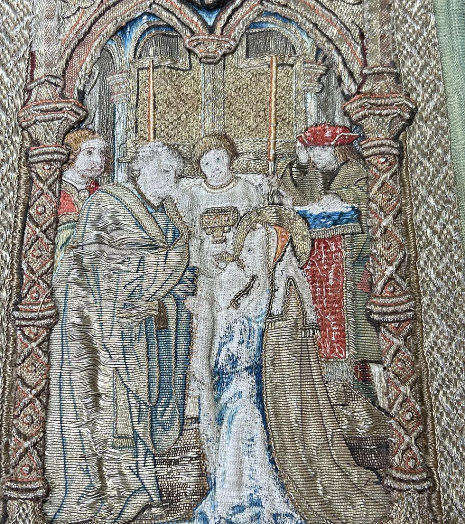 Embroidery close-up, woman receiving communion from church leader.