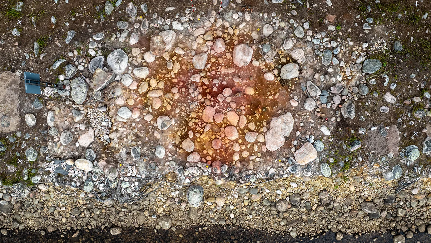 A pile of stones with red soil inte the middle