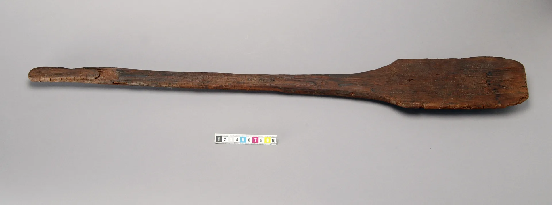 A reddish-brown wooden paddle