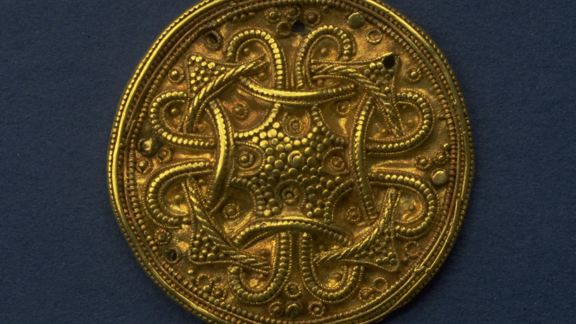 Guldmedaljong med sirligt mönster