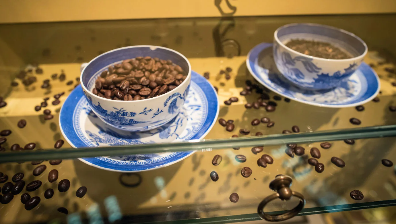 Två kaffekoppar med blått motiv i en monter.