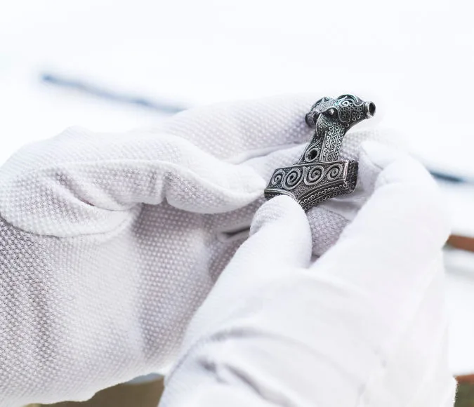 Hands with white gloves hold a Thor's hammer