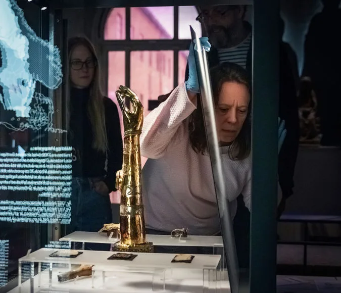 Museum staff opening a display case to examine an object.