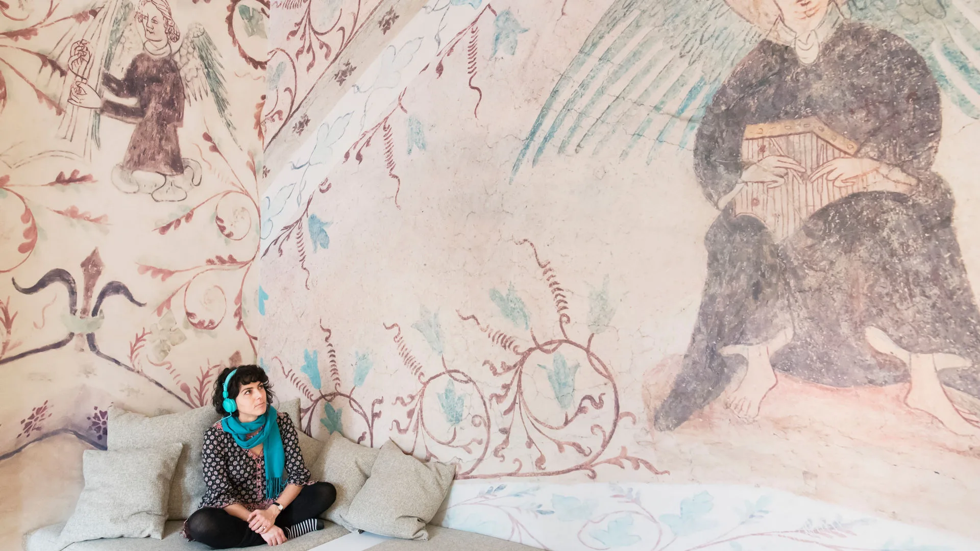Person wearing headphones sitting in front of a mural