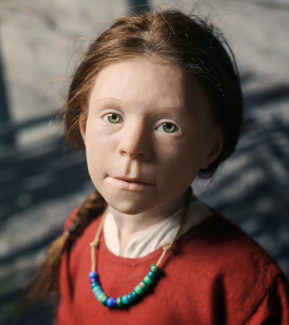 A silicone head of a girl with red dress and green eyes.