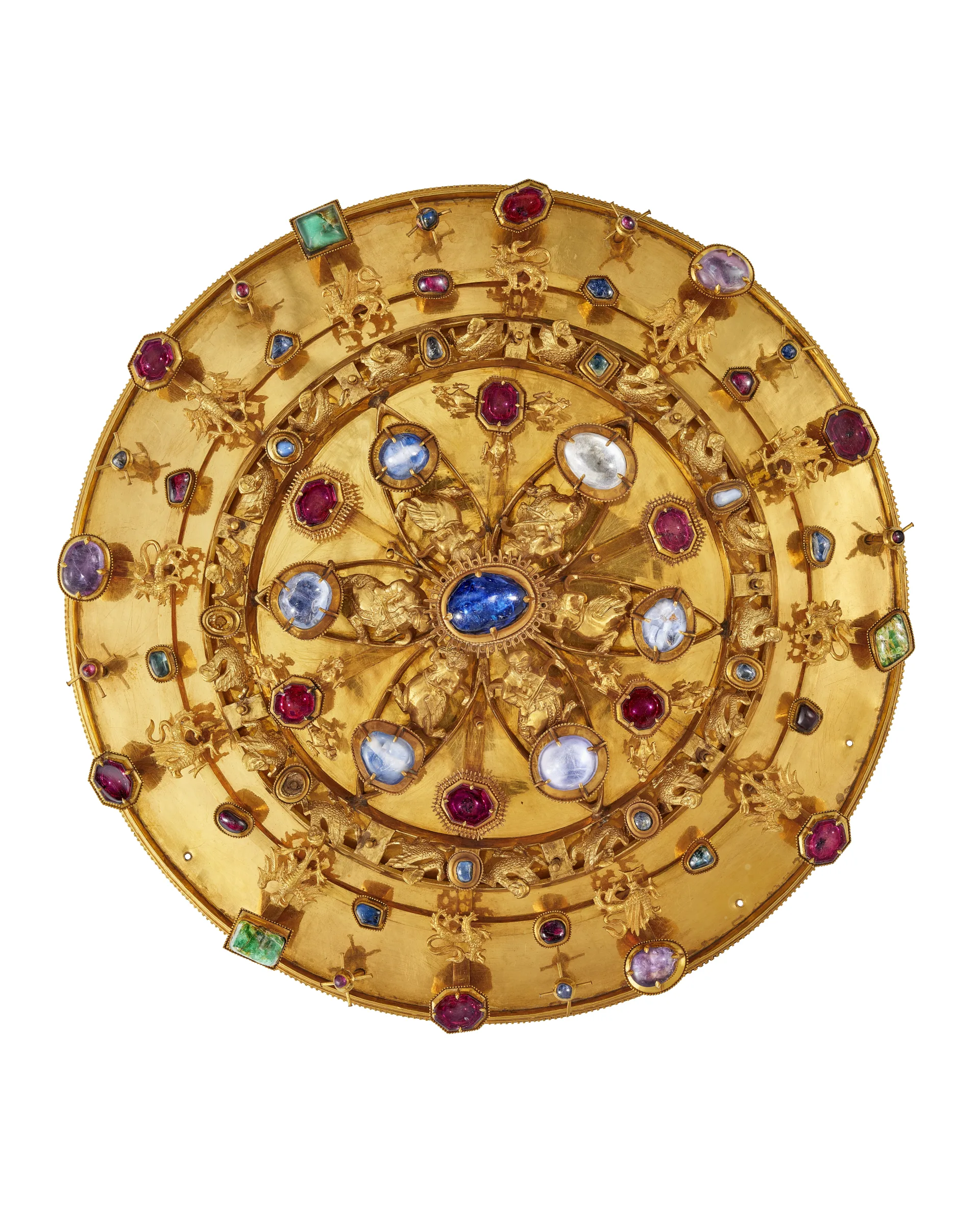 En rund spänne i guld. Stenar i olika färger.