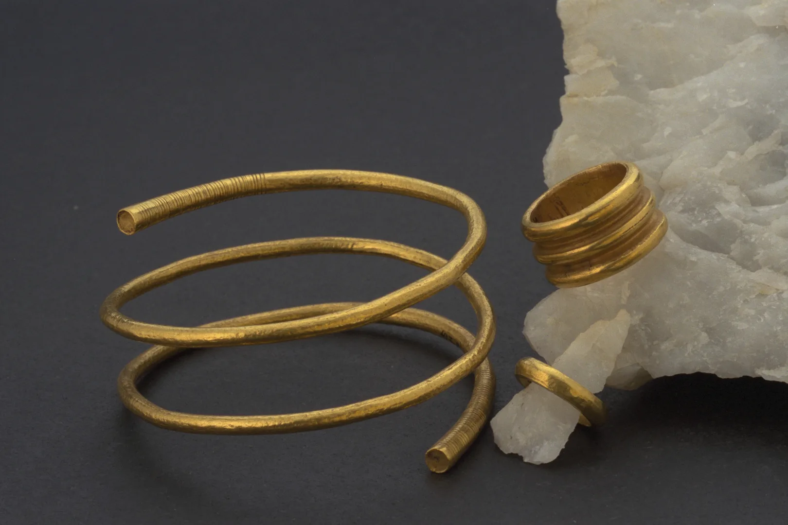 One gold spiral and two gold rings, one larger than the other.