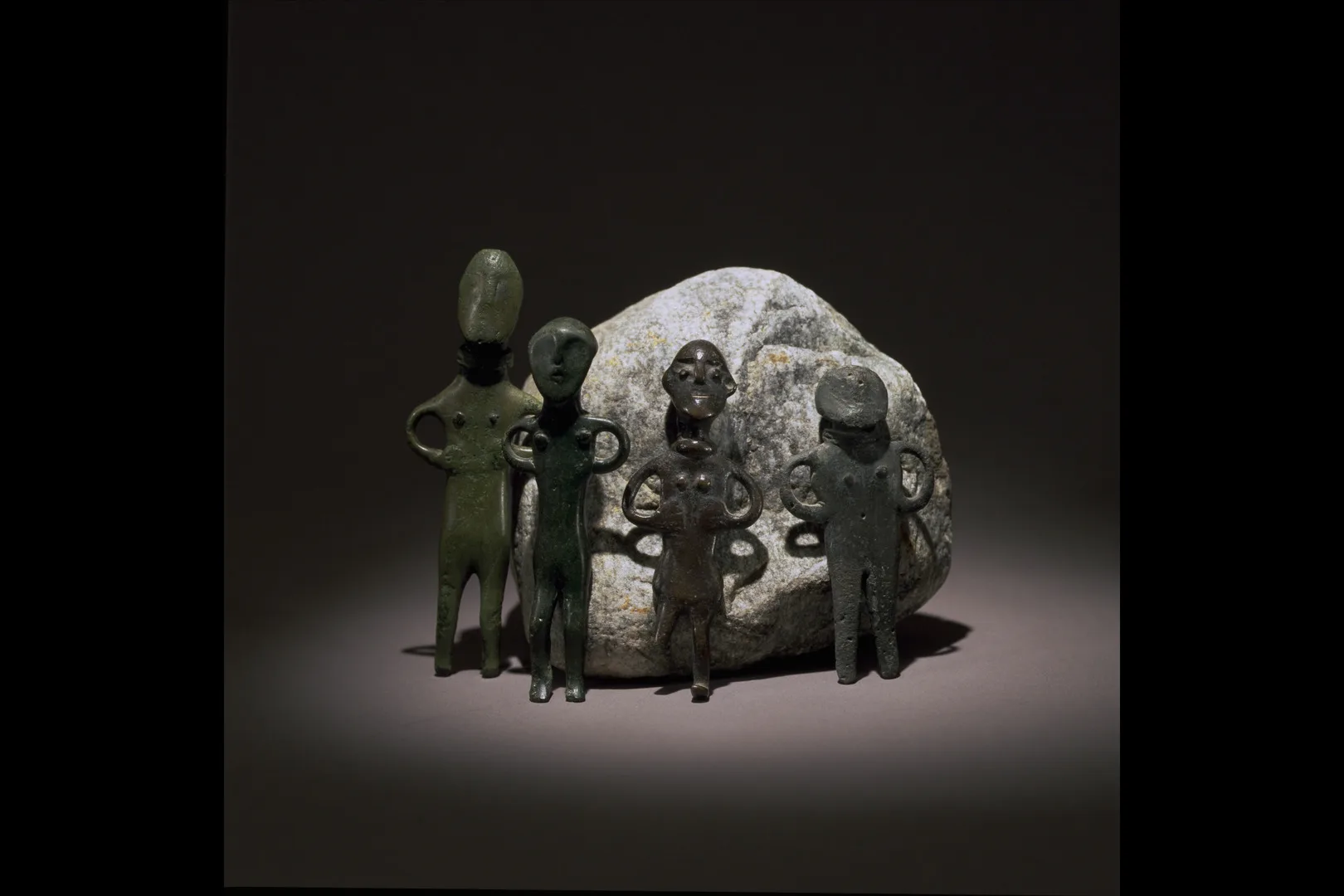 Small bronze figurines placed in front of a stone