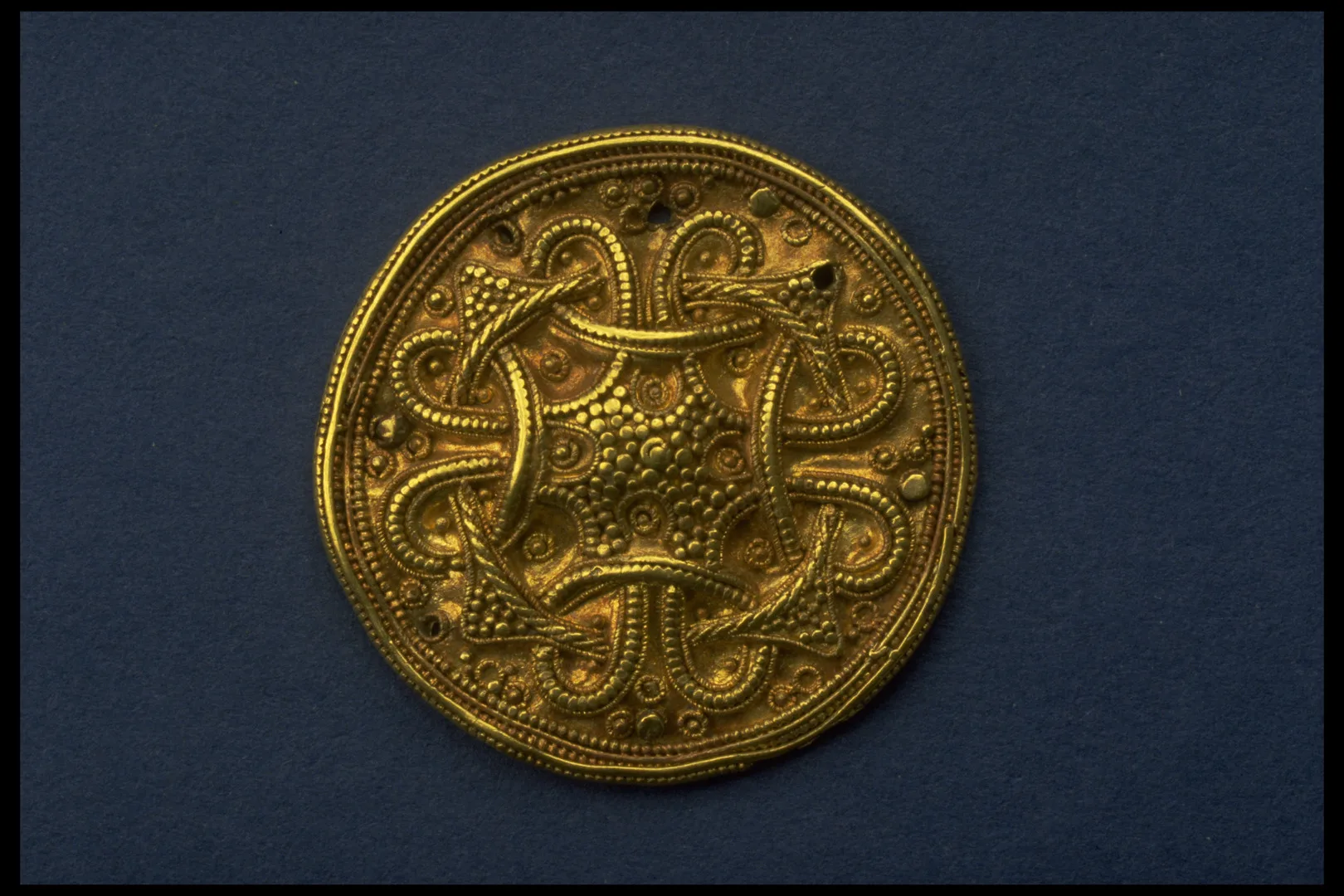 Ett dekorativt guldspänne med snirkliga mönster.