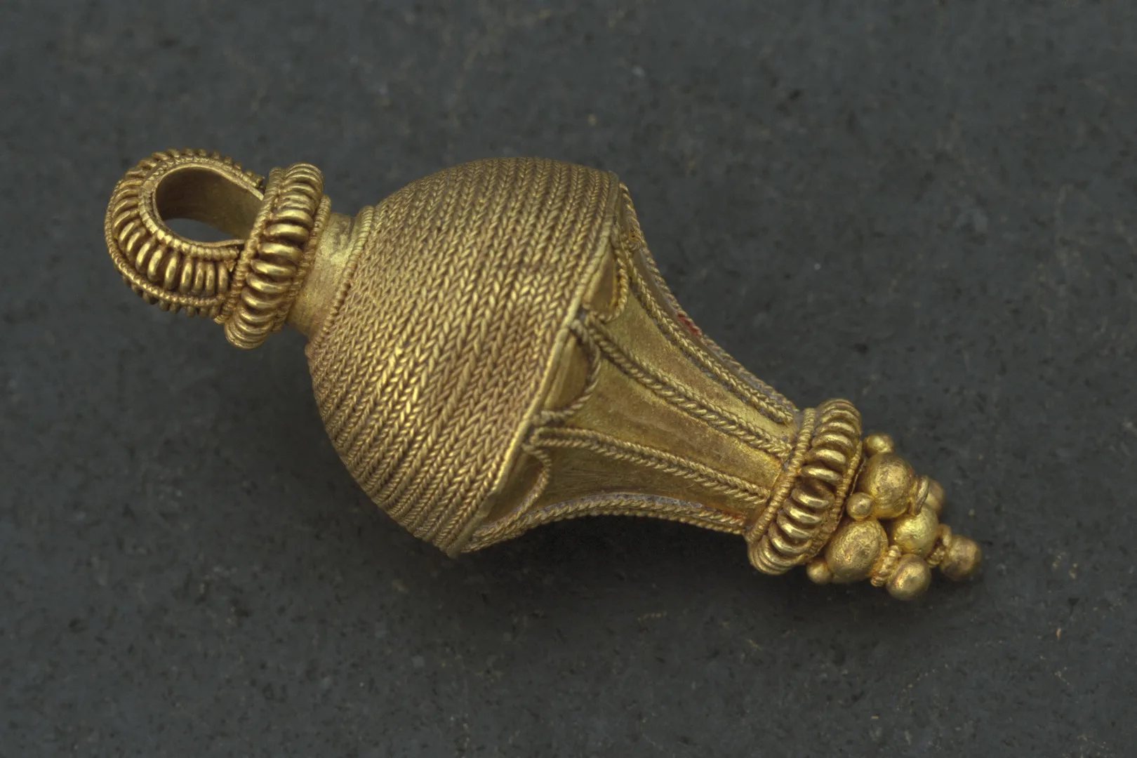 EN guldberlock dekorerad med guldtråd som liknar tvinnat rep. 