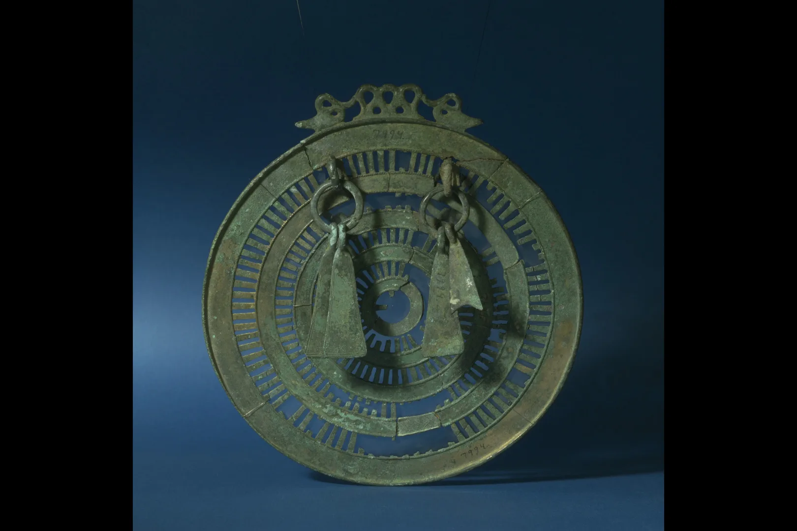 Cirkulärt bronsföremål med hängande dekorationer