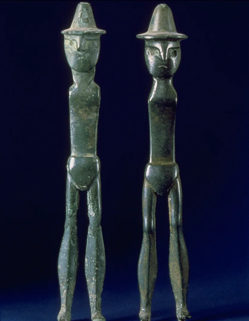 Two bronze figurines, interpreted to depict twins. Both are wearing hats.