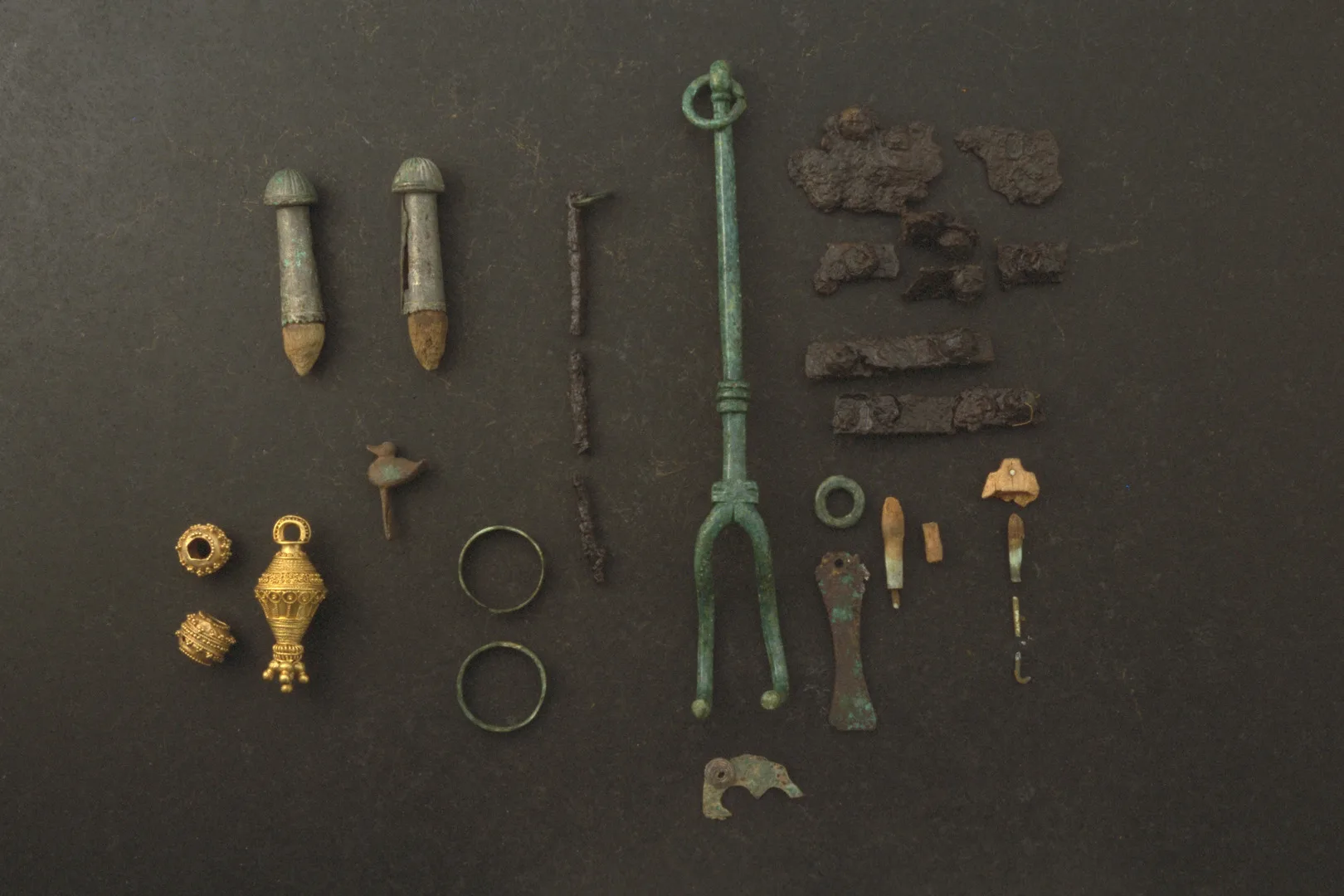 Grave finds, such as gold pendants, copper rings, an iron spindle rod, a spindle whorl and a small bronze duck.