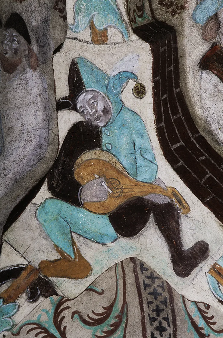 Person med kostym delat i två färger, med fiddla