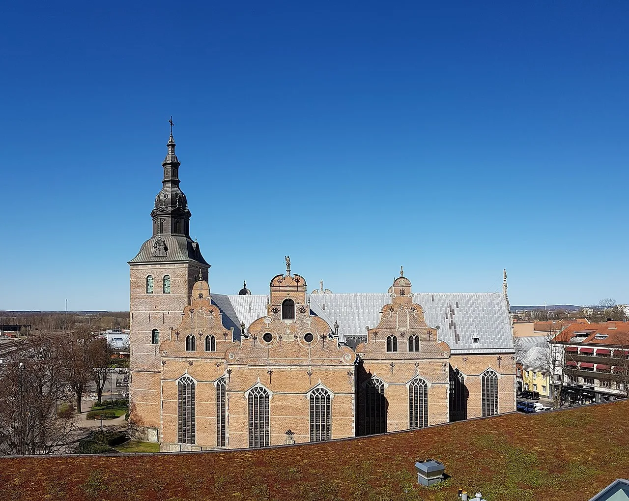 En stor stenkyrka med väldiga gavlar fotograferad mot en helt klarblå himmel.