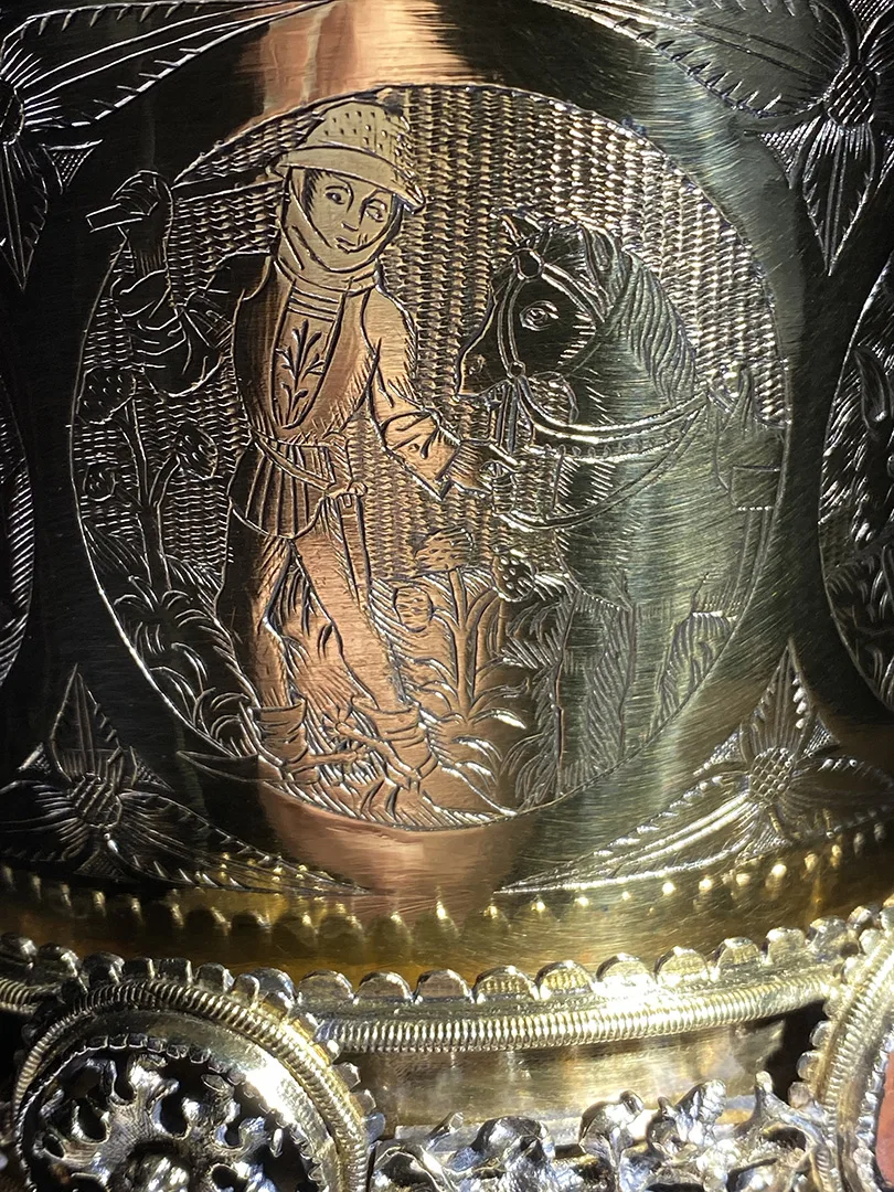 Engraved silver image of a person with a horse