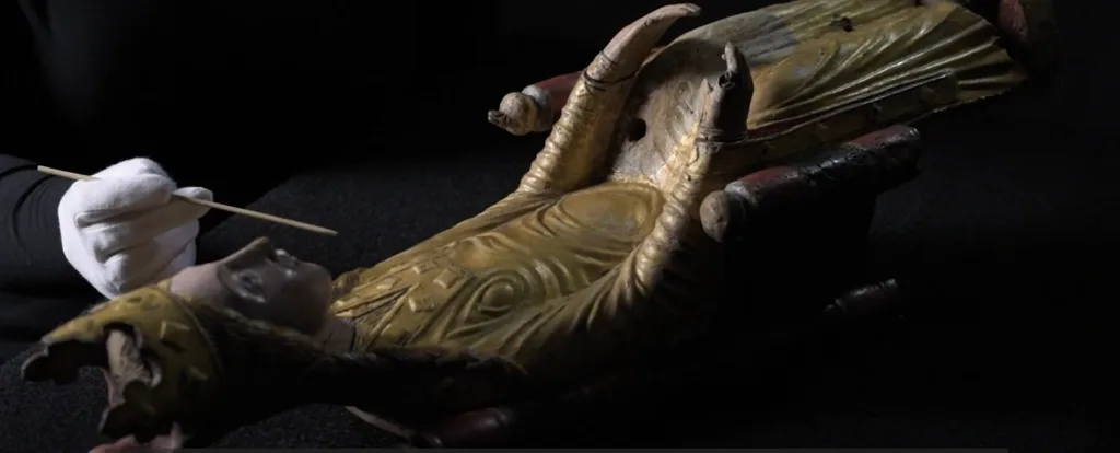 Wooden sculpture being examined by a museum employee