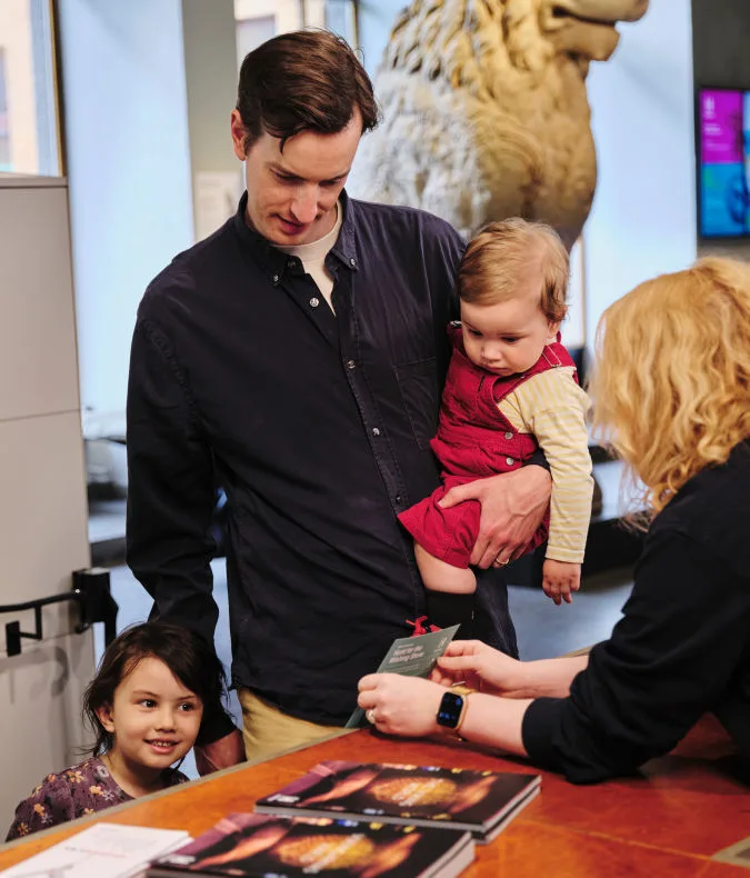En värd på Historiska museet visar en karta för en barnfamilj.
