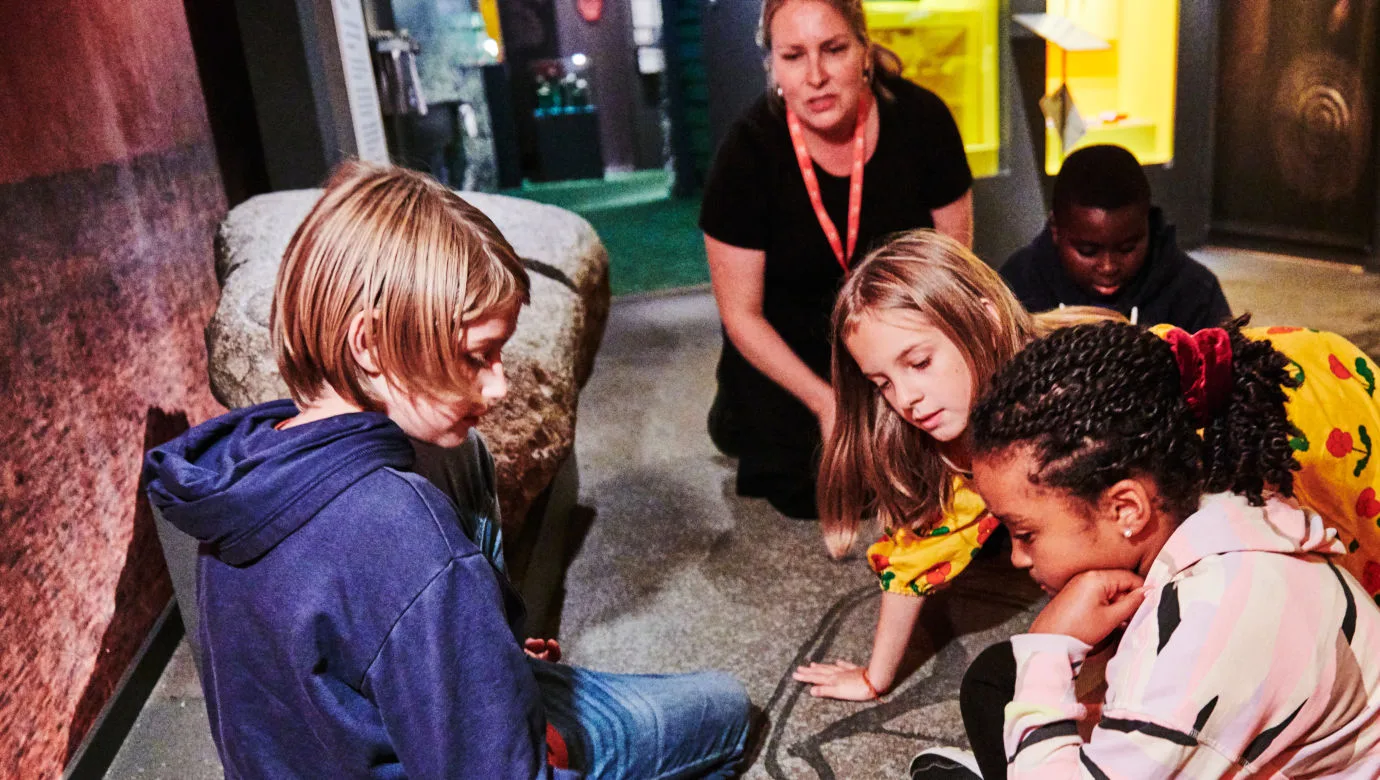 Elever tillsammans med en pedagog i utställningen Forntider.