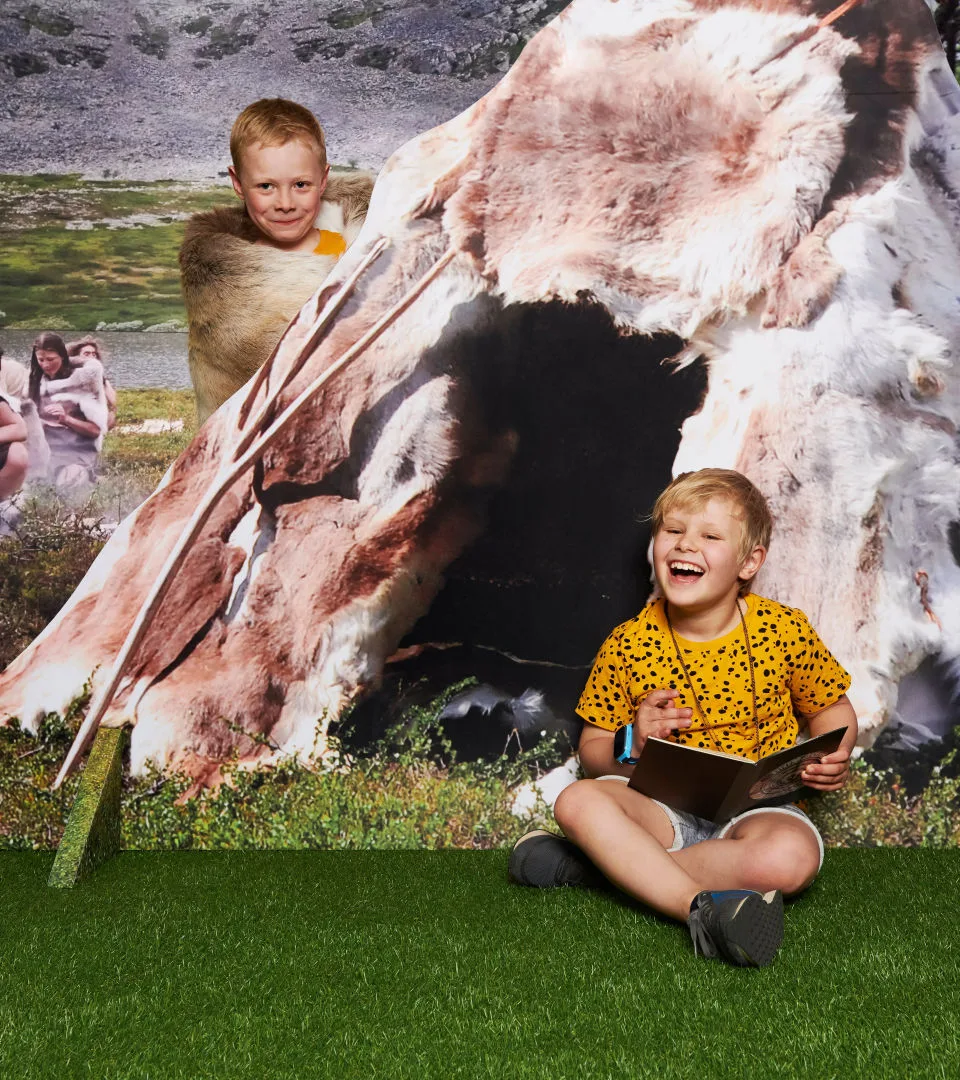 Två barn leker i forntidsrummet på Historiska museet.