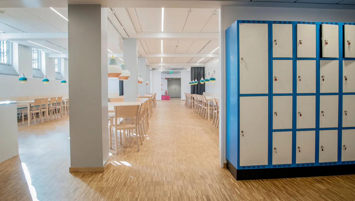 Tables and chairs. A shelf with lockable lockers for coats and bags.