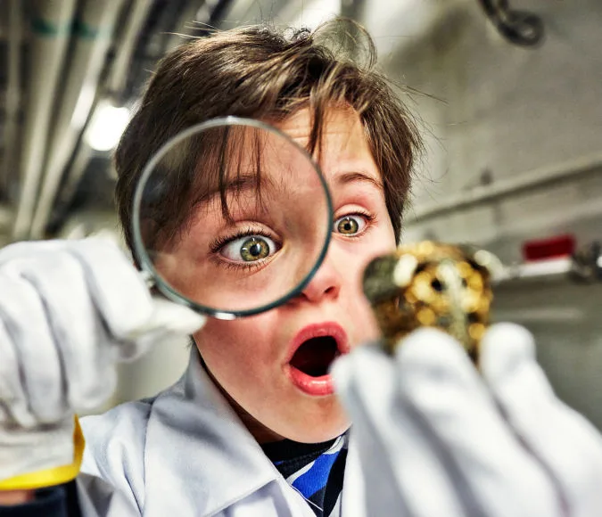 Barn undersöker föremål med ett förstoringsglas.