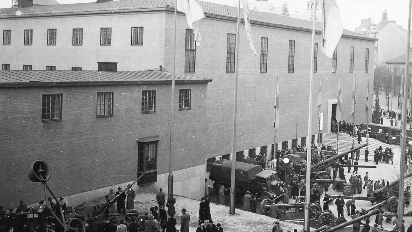 Människor står utanför museet. Flera fordon och föremål står utställda.