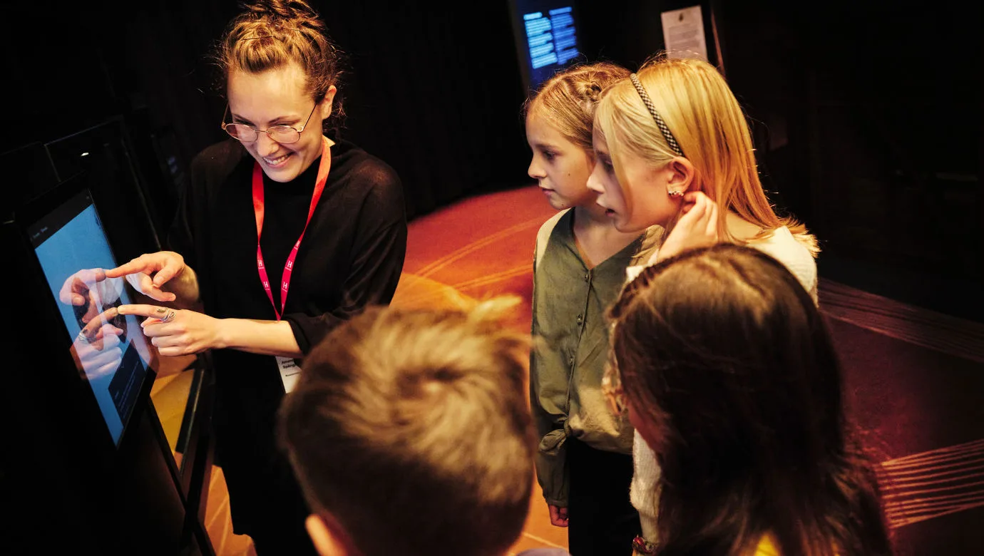 Pedagog visar eleverna ett föremål i utställningen Vikingarnas värld.