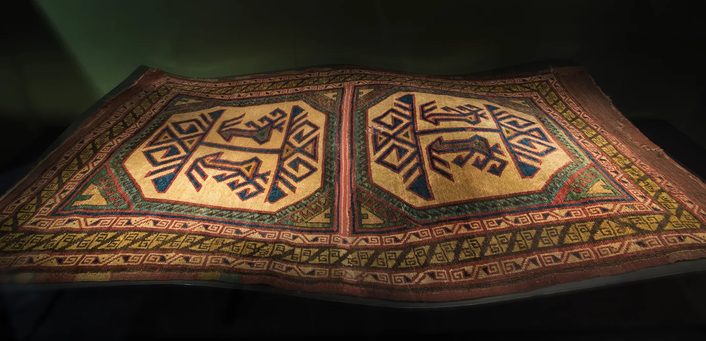 Matta med abstrakta figurer i rött, svart och beige.