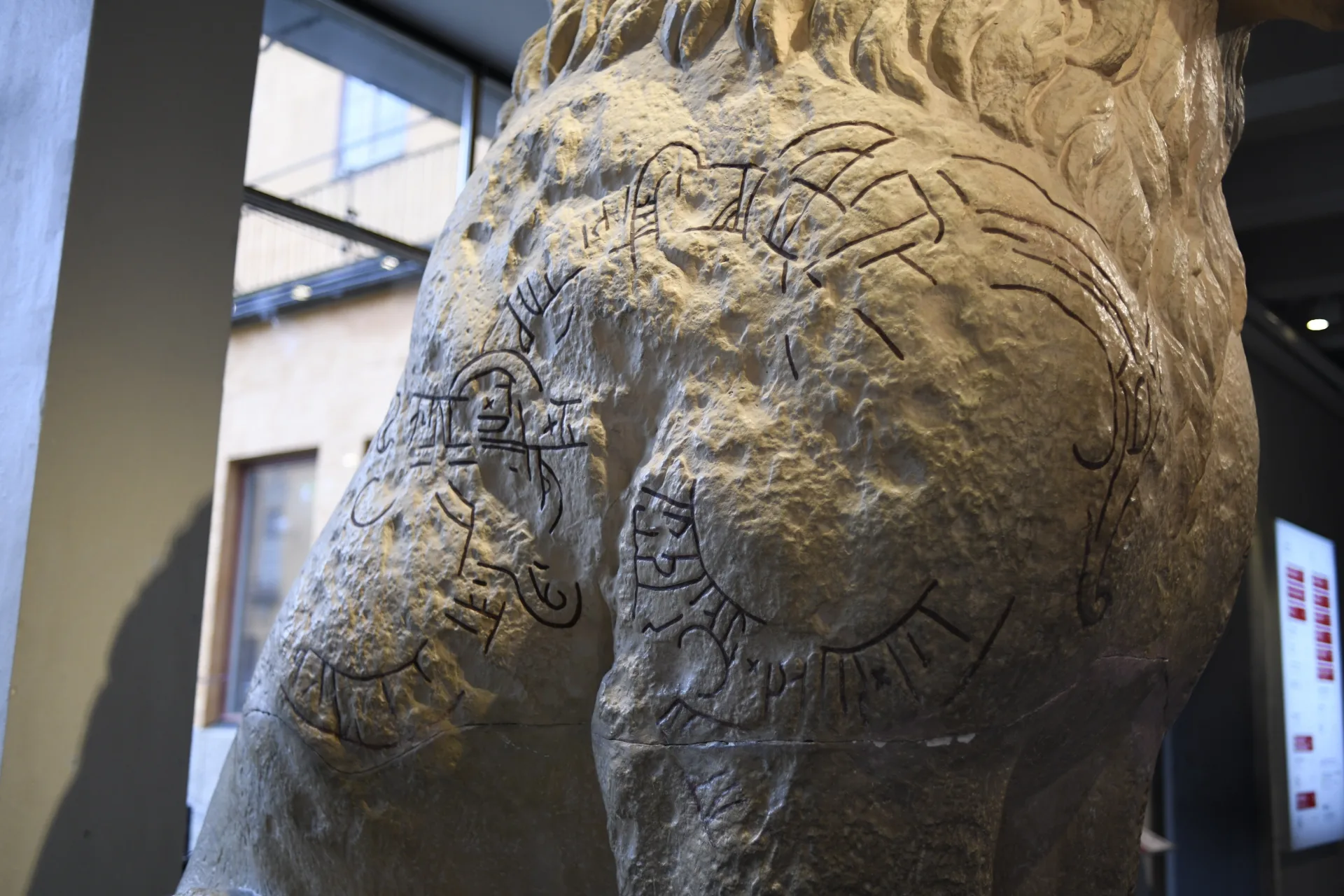 Detail of the plaster lion with partly visible runes.
