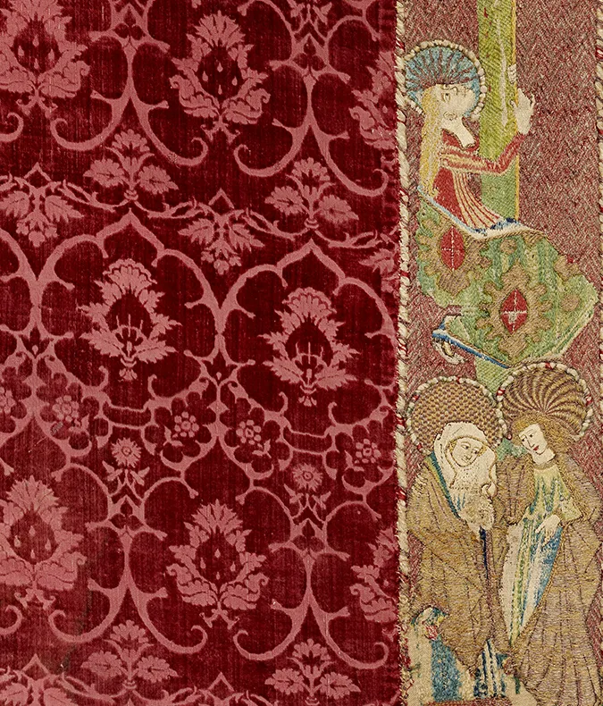 Organic pattern on red textile. Embroidred female figures.