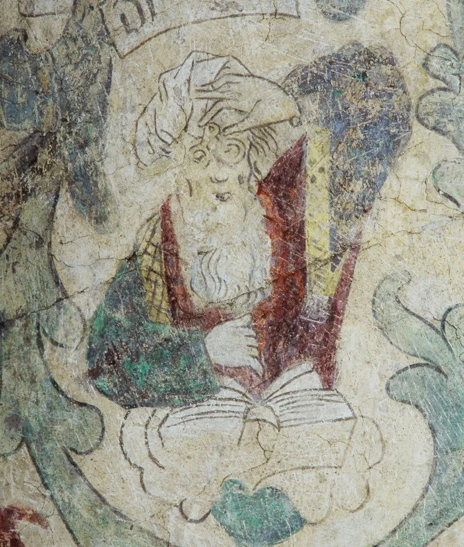 Person med huvdbonad och glasögon håller en bok