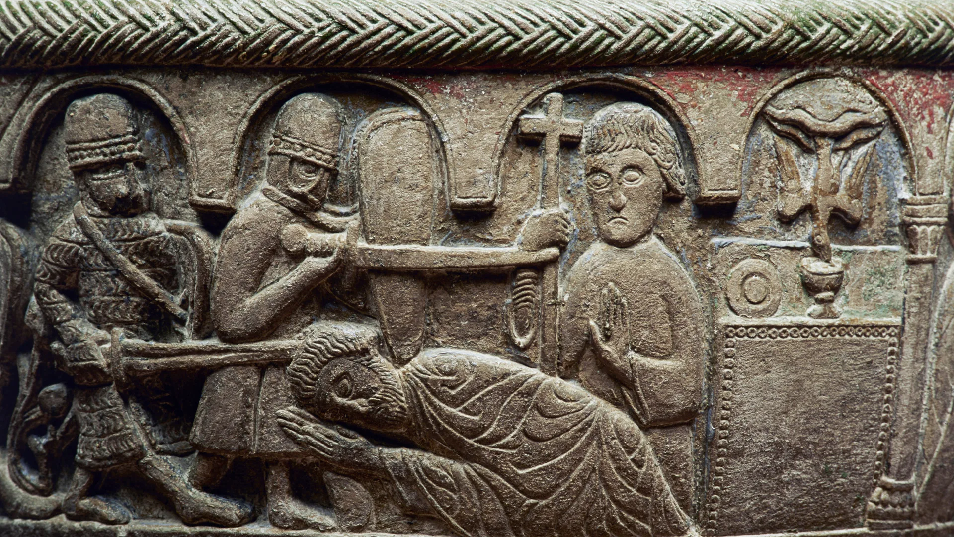 Bild inhugget i sten, visar en person som ska dödas med svärd