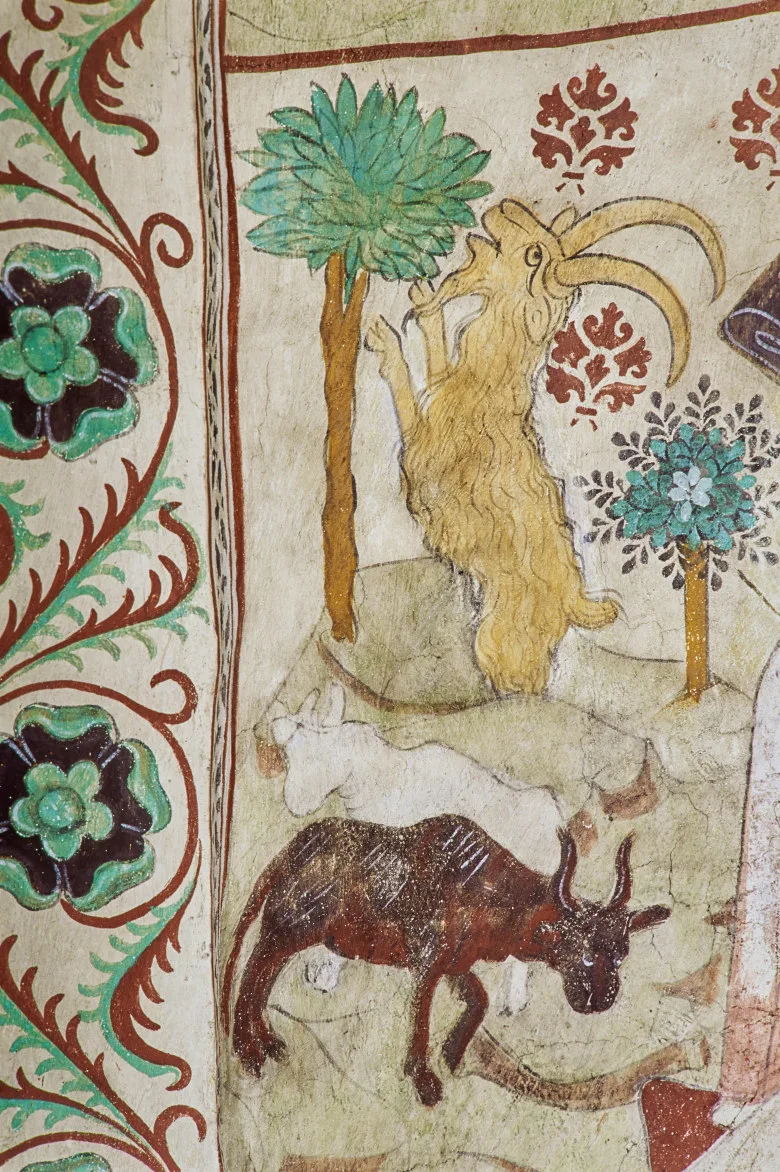 Painting of a goat eating leafs from a tree