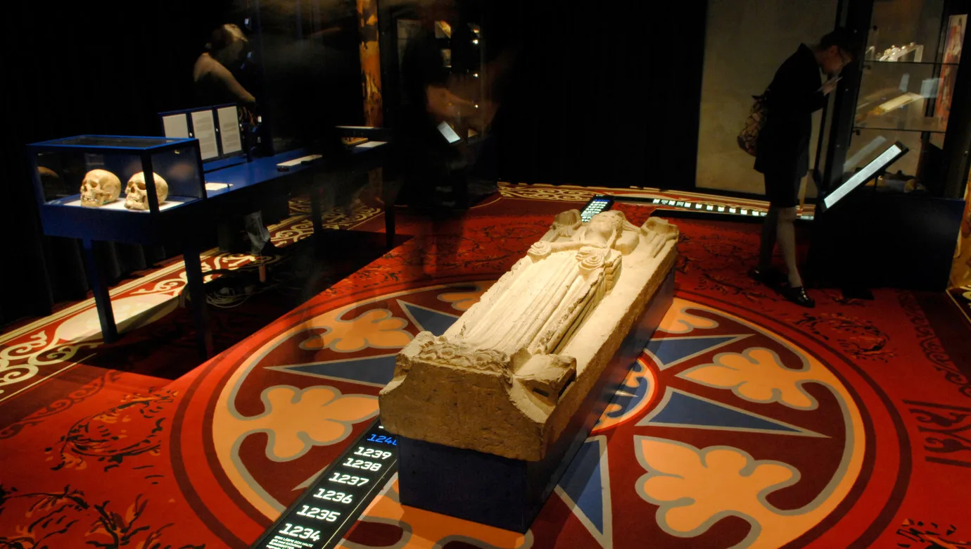 Gravtumba eller sten med skulptur av en kvinna med krona