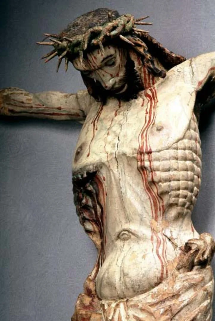 A wooden sculpture of an emaciated man, bleeding from his head and body.